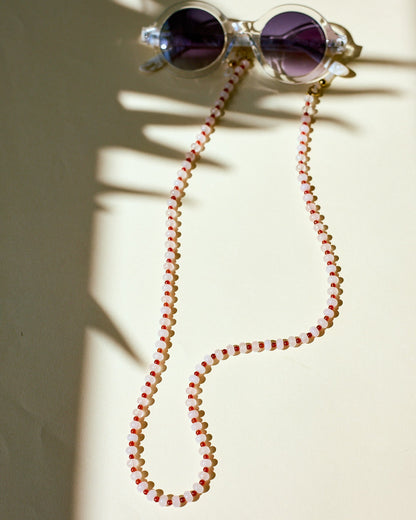 Sunglasses with a red and white beaded sunglasses chain on a light background